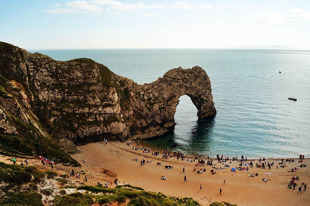 Durdle Door Beach on Dorset and East Devon coast: a beach with, at one end, a large natural rock arch, carved by the sea.