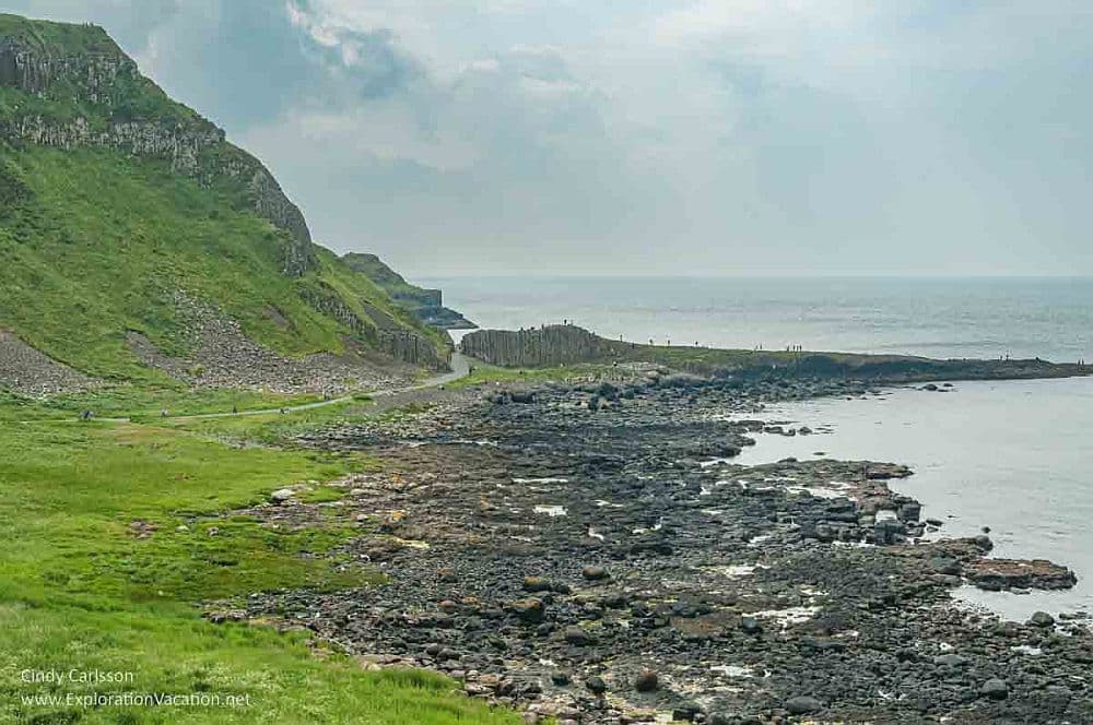 View along the rocky coast to the Giant's Causeway, with the sea on the right and the cliffs on the left.