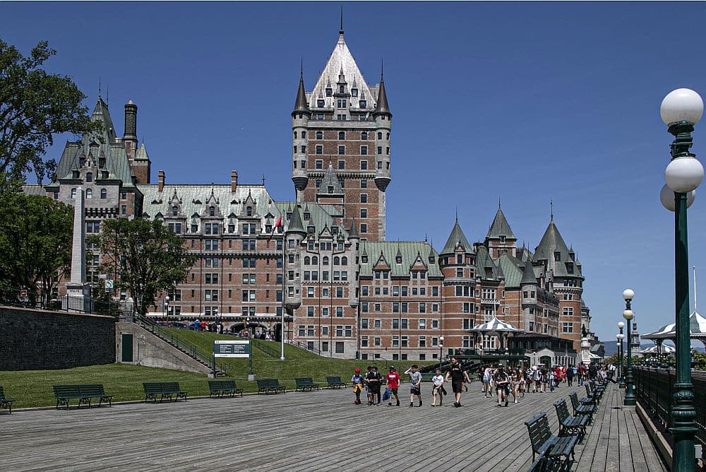 An open space for pedestrians in the foreground, an impressive castle-like building in the background with a tall and wide tower.