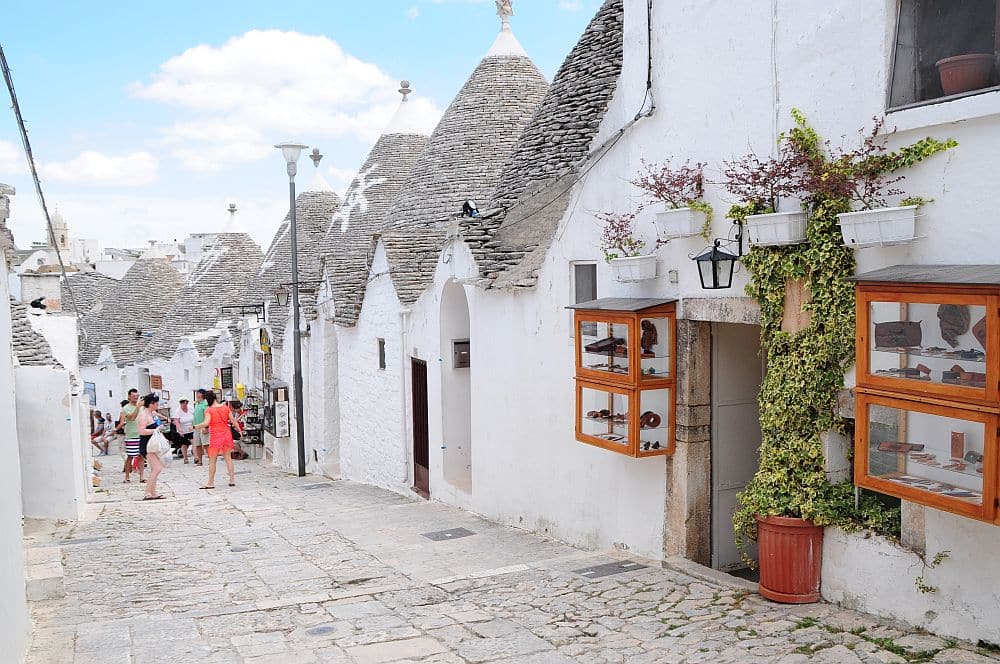 Trulli of Alberobello: A row of whitewashed houses with conical grey slate roofs.