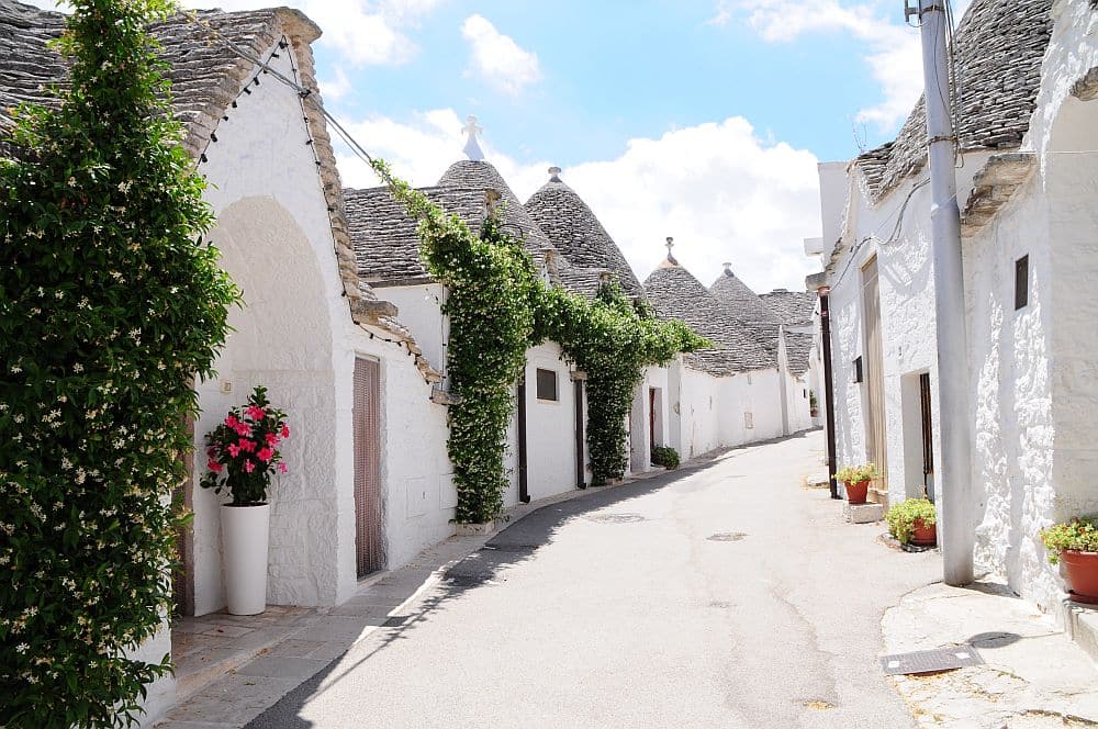 Trulli of Alberobello: Looking down a street with whitewashed houses on both sides, each with conical slate roof.