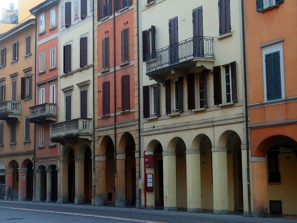 A row of buildings in Bologna each have slightly different porticos, but they cover the whole length of the sidewalk.