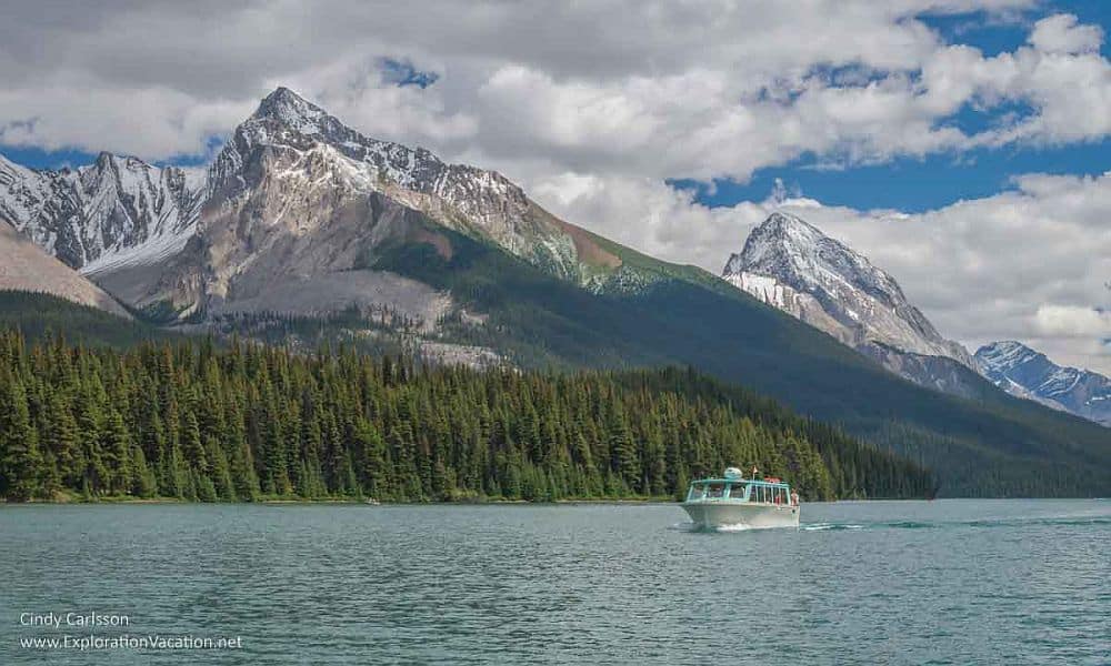 Canadian Rocky Mountain Parks: A lake with a small motorboat. Behind are two snow-topped mountain peaks.
