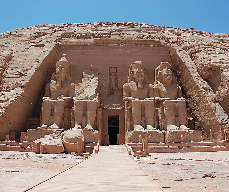 Four huge sitting statues, with a doorway - about 3x higher than a person and reaching to knee height on the statues - in the center. At Ramses Temple, Nubian Monuments