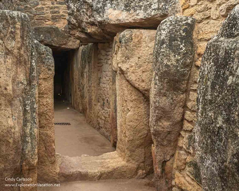 A tunnel of sorts formed from large slabs of stones intermixed with areas that are made of stacked stones.