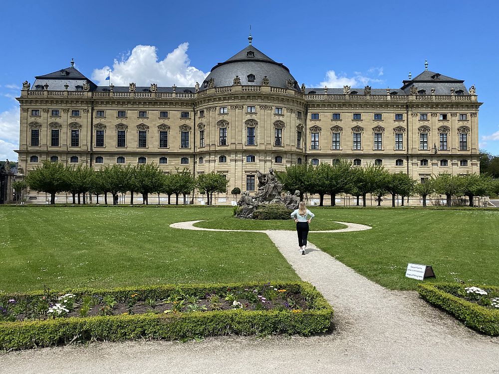 Full front view of the Wurzburg Residence: a massive palace, several stories tall and 21 windows across. A symmetrical design with a round dome above the entrance and smaller domes at each end.