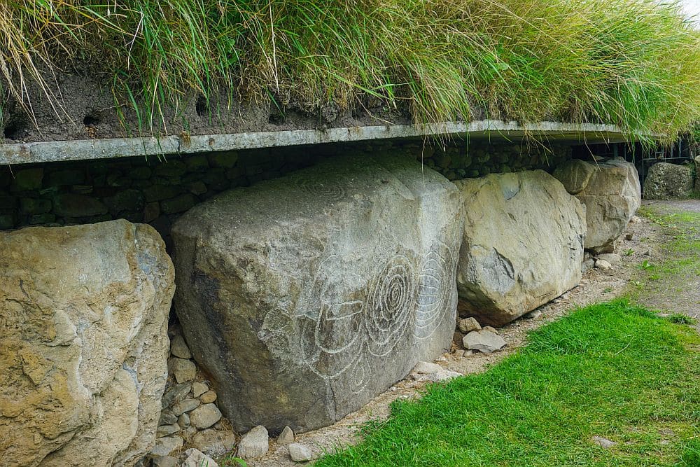 A stone on the side of one of the burial mounds has a visible petroglyph: carved in the shape of three connected circles with patterns inside them.