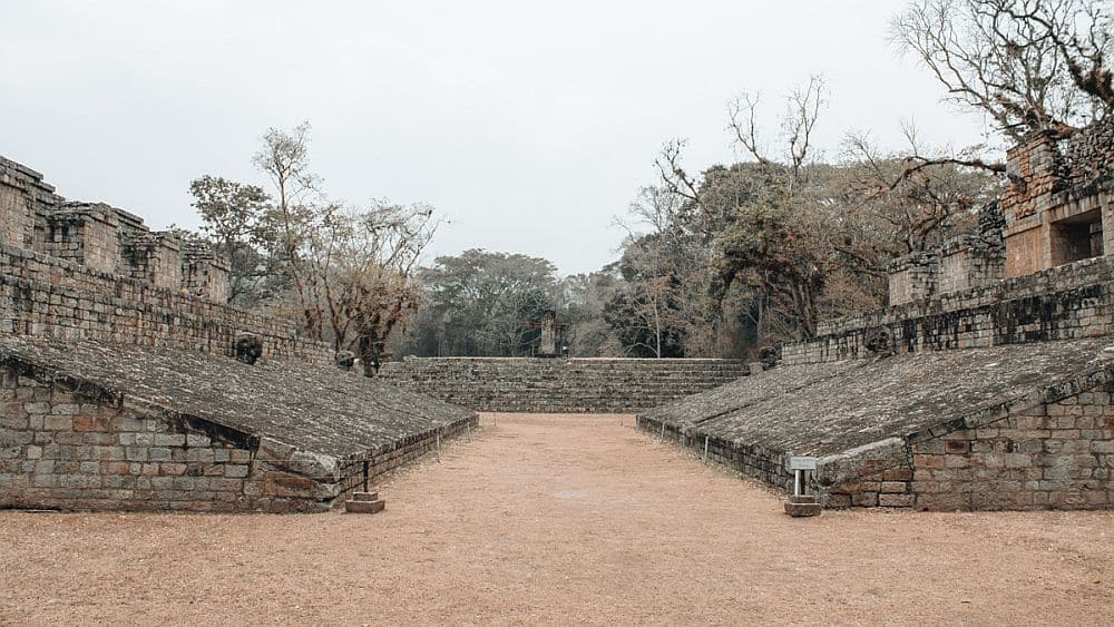 A space between two stone structures at Copan, on each side a steeply slanted wall.