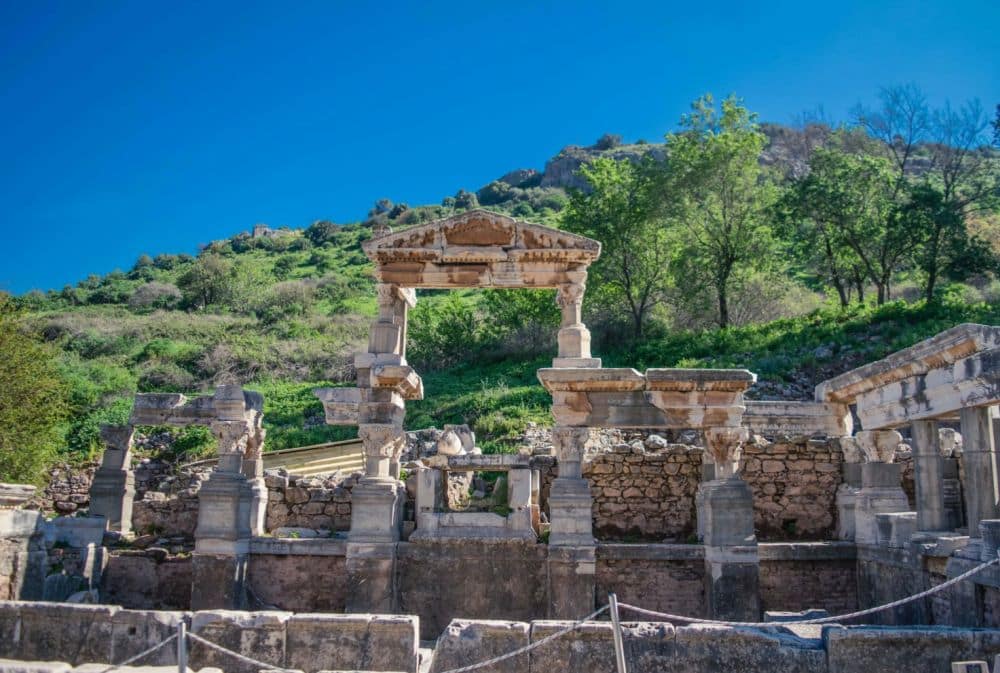 What remains of the Fountain of Trajan at Ephesus: a few columns, two of them holding up a triangular pediment.