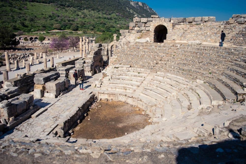 A semi-circular amphitheater of stone, with tiered stone seats in a semi-circle around what was once the stage.