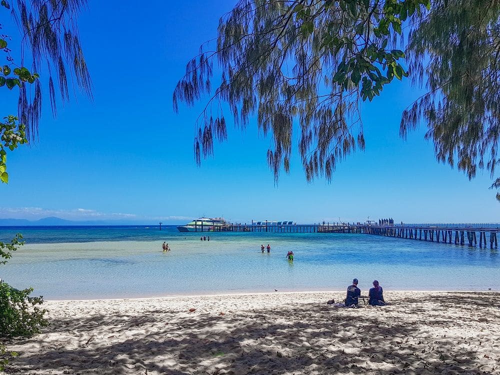 A white-sand beach looking toward calm blue water.