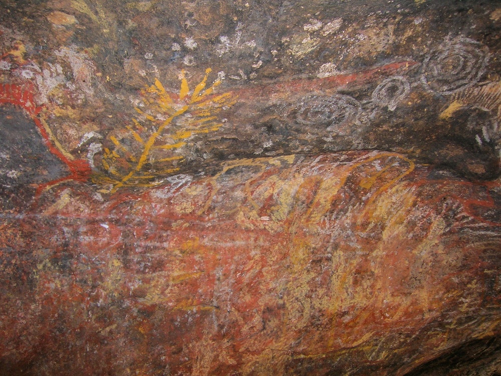 Rock paintings at Uluru are hard to make out, but there are some yellow branch images and white spirals and lots of faded colors.