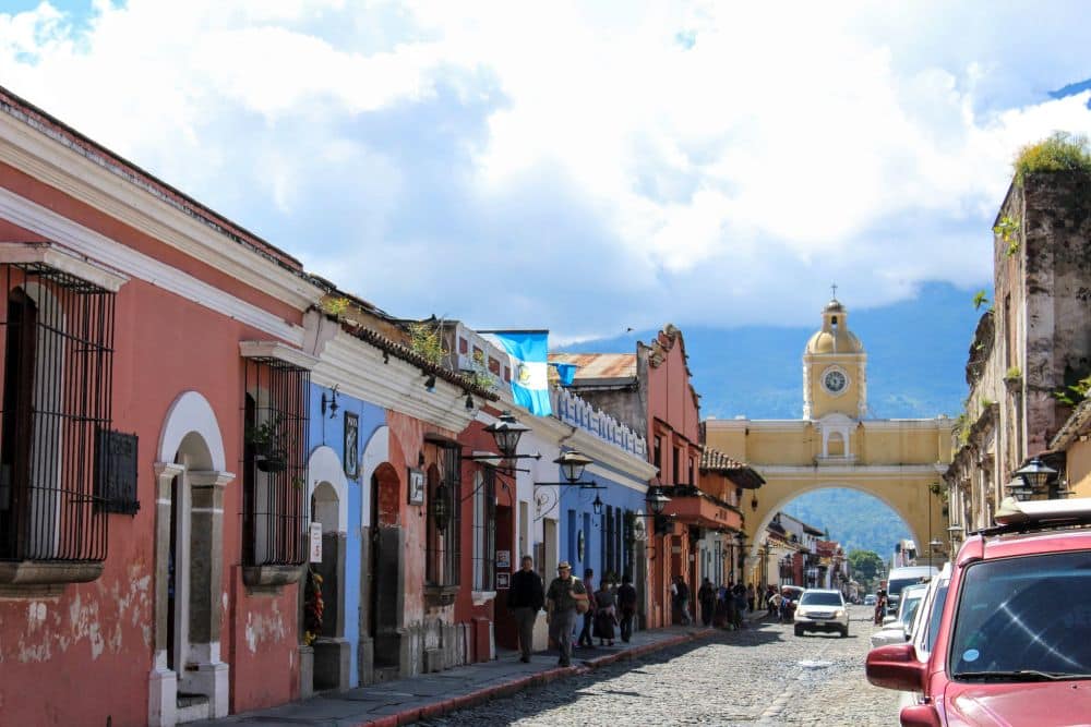 Looking down a street of single-story shops painted in bright colors, with the Santa Catalina Archway at the end of the row.