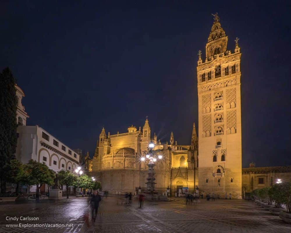 Seville Cathedral at night, with its very tall square tower lit up.