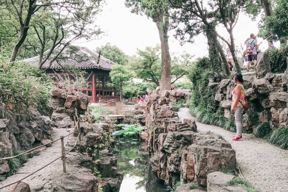 Inside the Lion Grove, a stream, a path next to it, a small pavilion in the background.