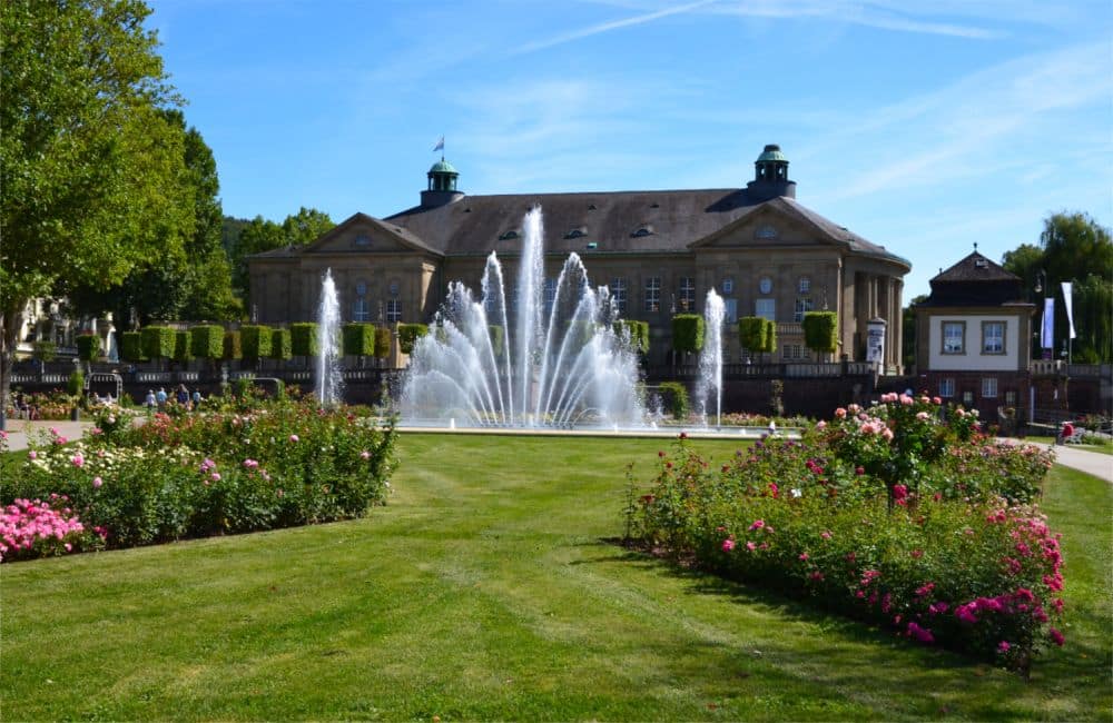 A stately building, with in front of it a fountain.