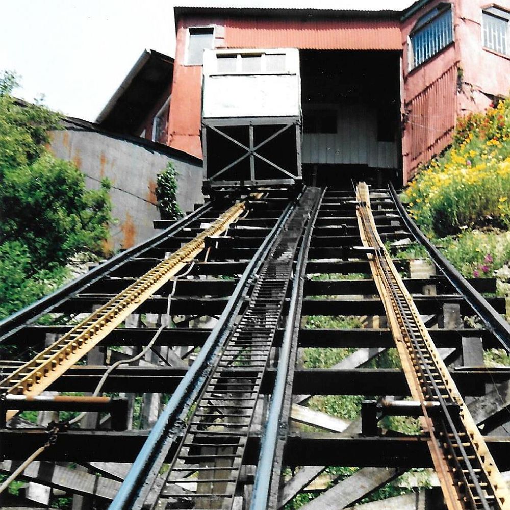 Looking up the track of one of the funiculars in Valparaiso. At the top, a red building where the funicular stops.