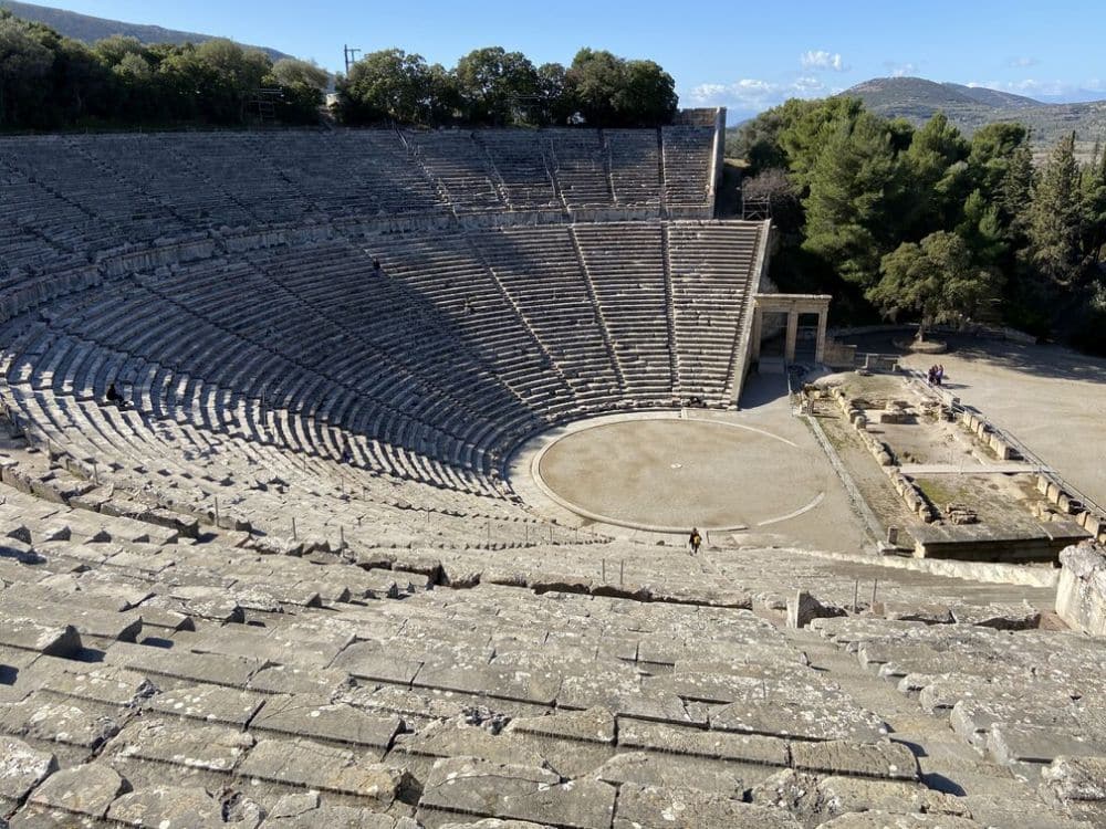 Semi-circular rings of stone benches slant down to the circular stage area at the bottom.