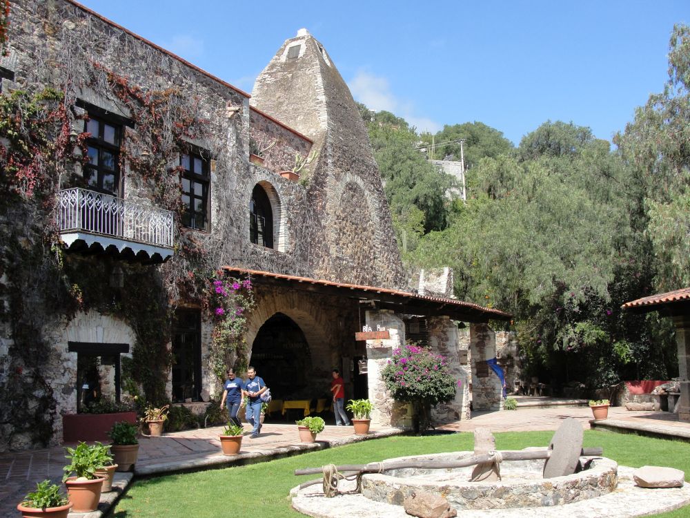 A two-story stone building with a wide shaded entrance space.