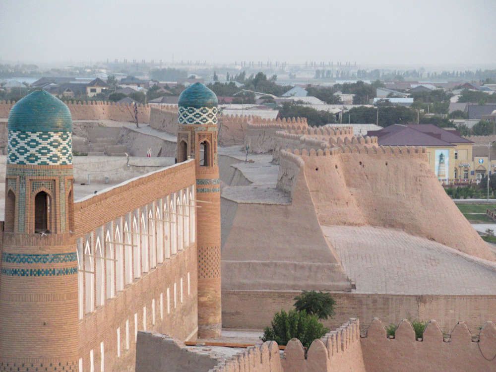 Looking along a defensive wall, which is extremely wide, with a smaller wall on top of it that zigzags, and that has crenellations along its top edge.