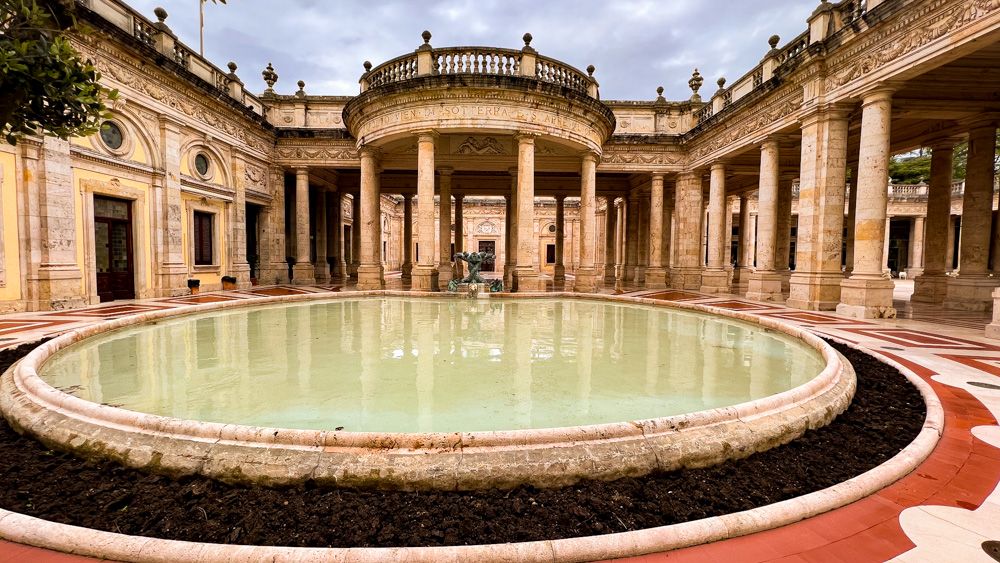 A pillared building with a shallow pool in front of it.