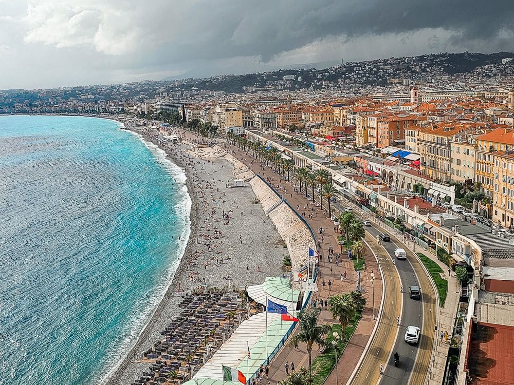 A view along Nice's beach, which has a walkway along it, then a road, then buildings.
