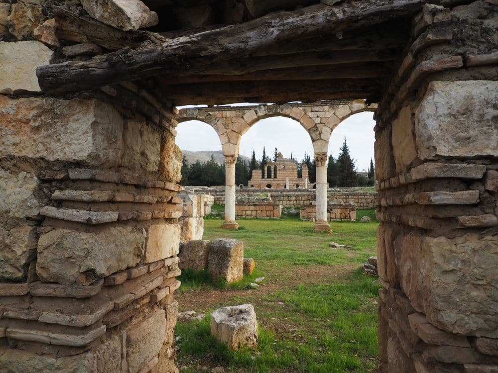 Looking through a thick stone doorway to a row of arches and through them to the palace in the distance.