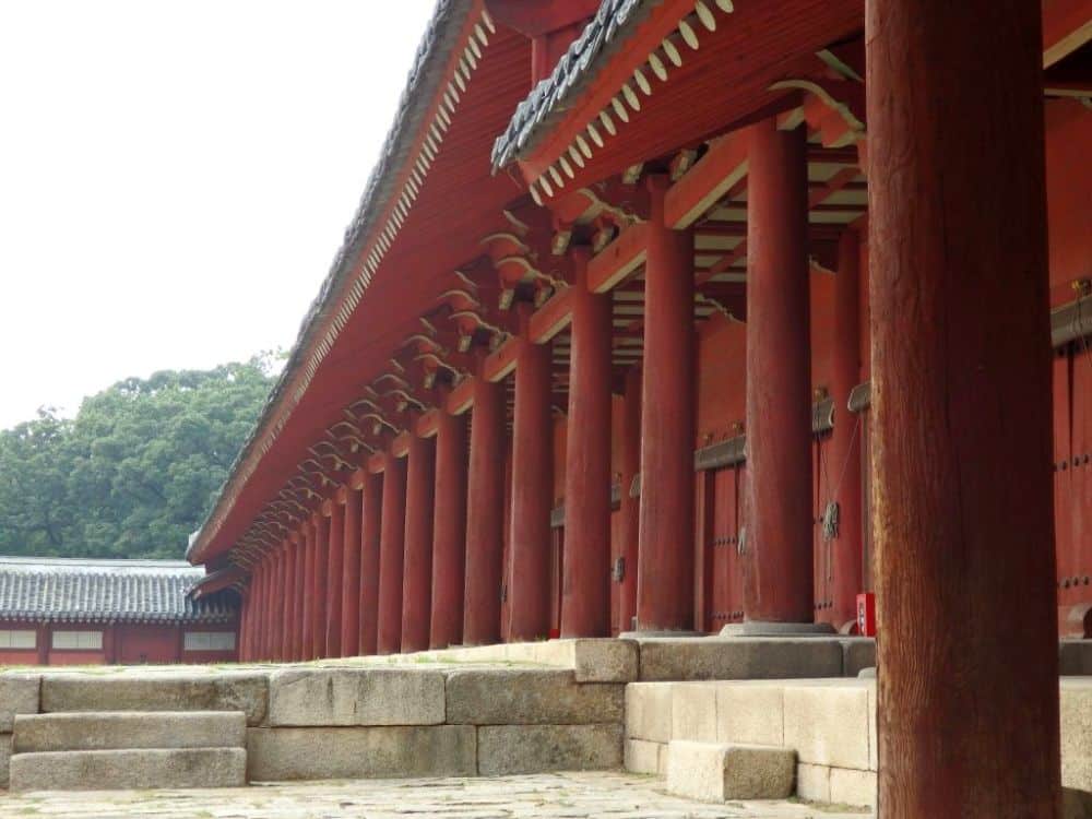 Seen from an angle, one of the main buildings of the Jongmyo Shrine: painted red with a row of pillars holding up the roof eaves.