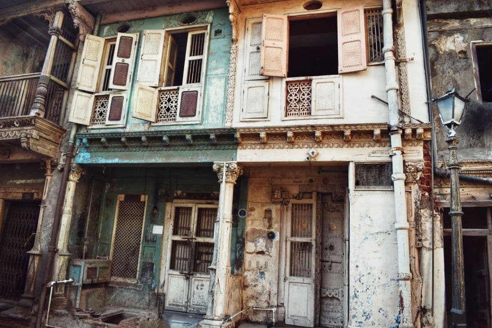 Two row houses of two stories, made of wood, with wood pillars in front.