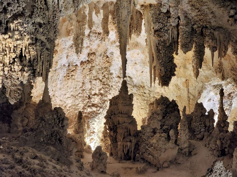A view of some stalactites and stalagmites backlit inside the cave.