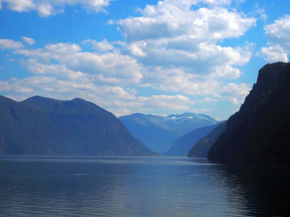 Calm water, steep mountains on both sides and a slightly snow-capped mountain straight ahead.