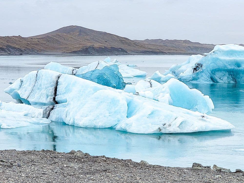 Pieces of ice, a bit blue, float on still water.