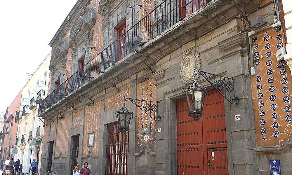 A building with two stories and many decorative elements on the facade, particularly patterns of tiling in bright colors.