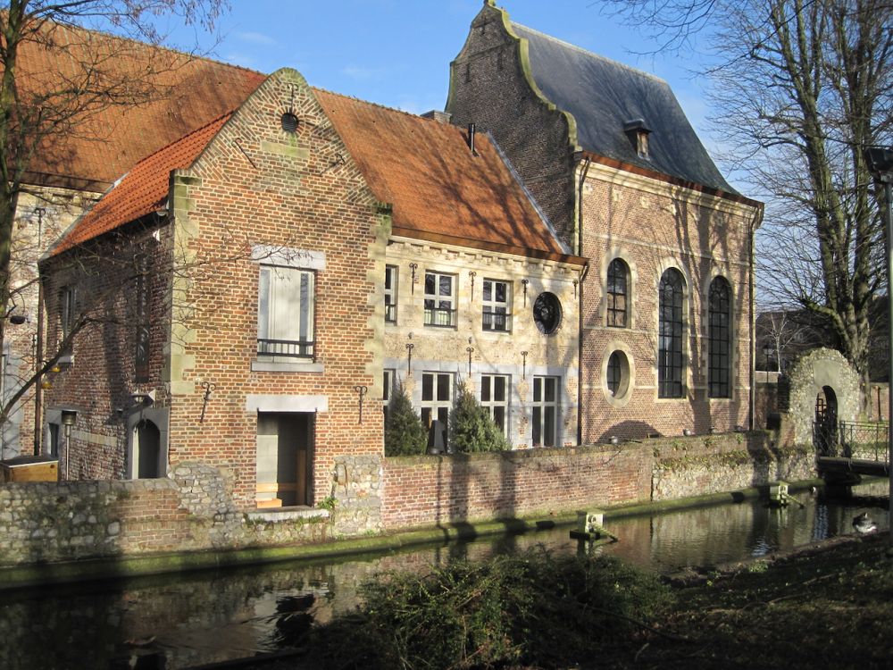 A brick row of buildings, each a slightly different style in brick and stone, bordering on a canal.