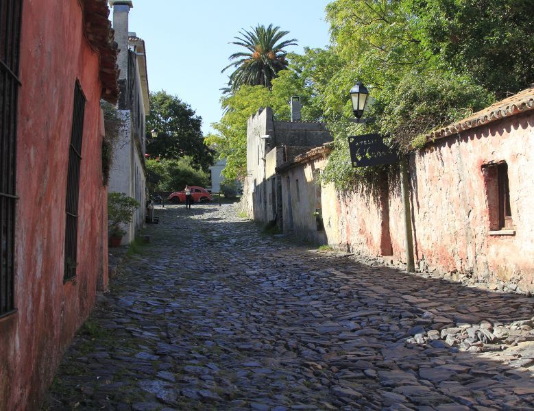 View up a cobbled street, low adobe houses on either side.