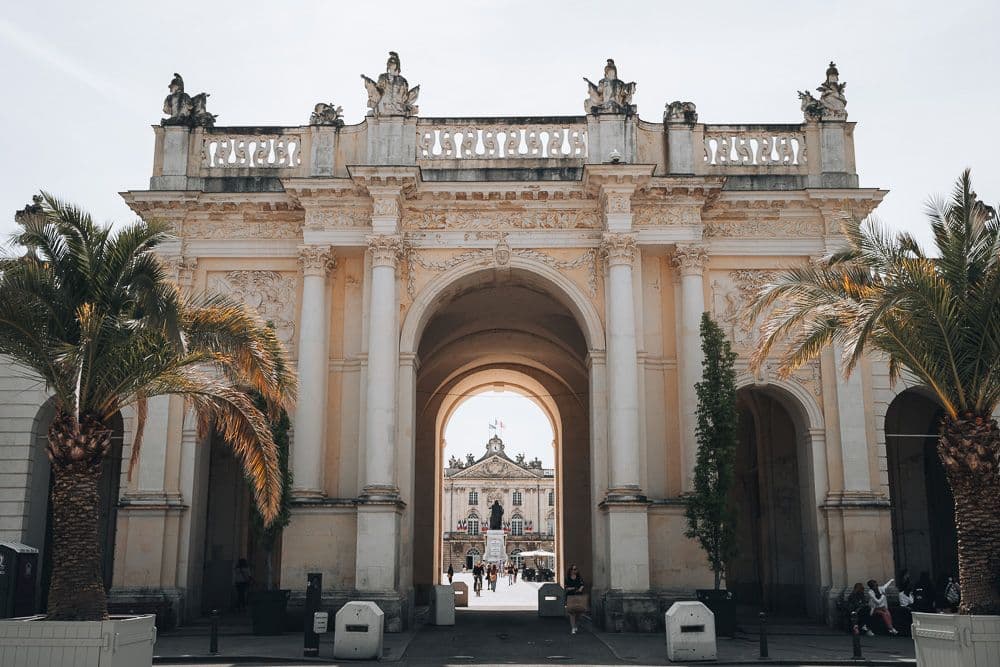 A larg archway in the center, flancked by smaller archways on either side. Through the central archway, a view to a large plaza.