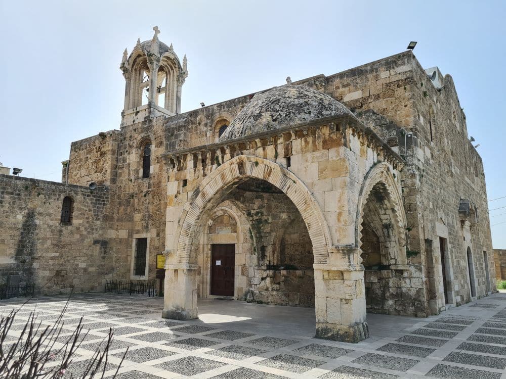 A Romanesque church, round arched entryway open on three sides, a small tower.