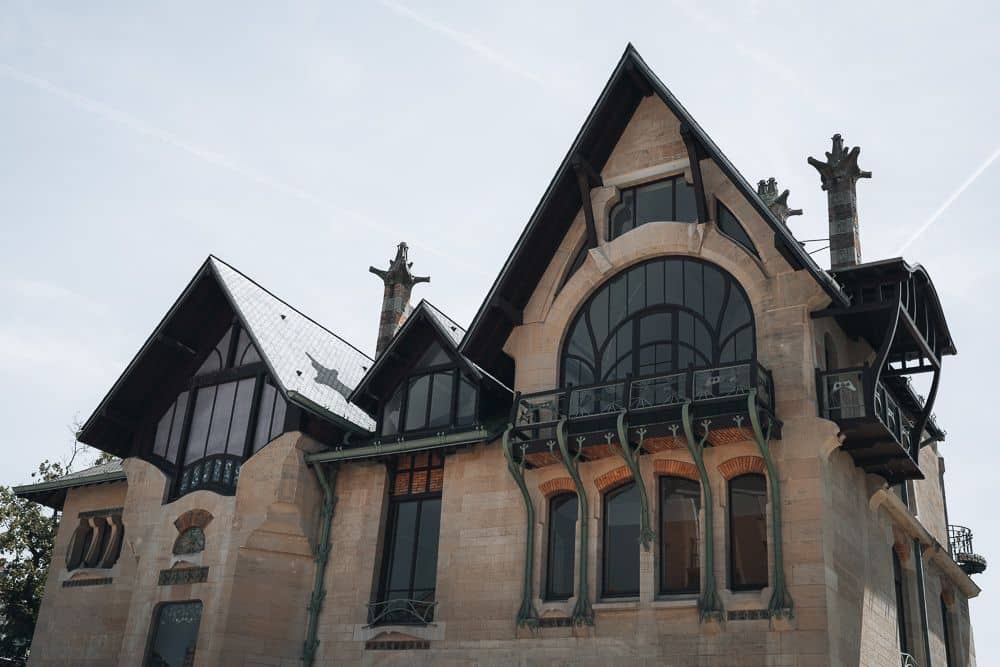 A villa made of stone with elegant curved windows and balcony supports in art nouveau style.