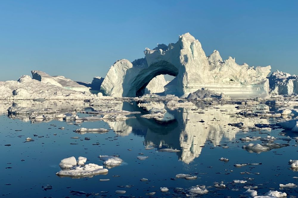 An arch of ice on very smooth reflective water.