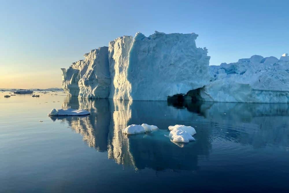 A large blockish iceberg with a low sun tinging it yellow.