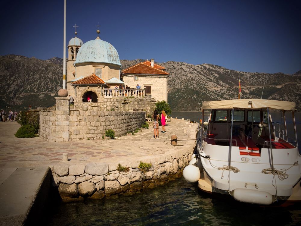 A small church with a dome, a boat moored beside it.