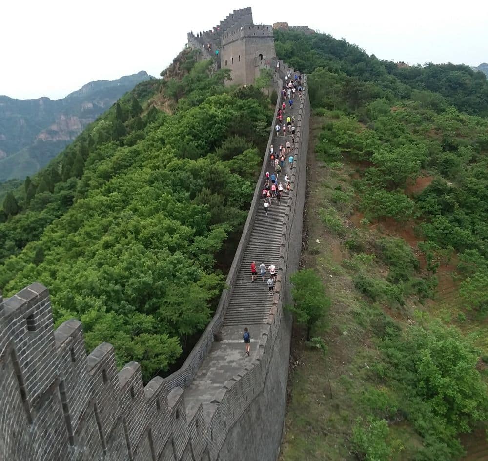 A view along a section of the wall, going down one hill and then up another. A scattering of people along the top of it.