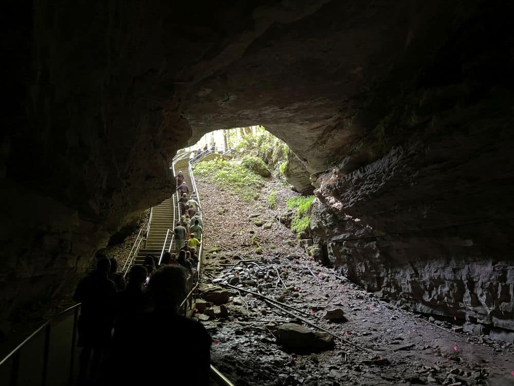 Looking out the entrance to the cave, people on a walkway on the left looking very small.
