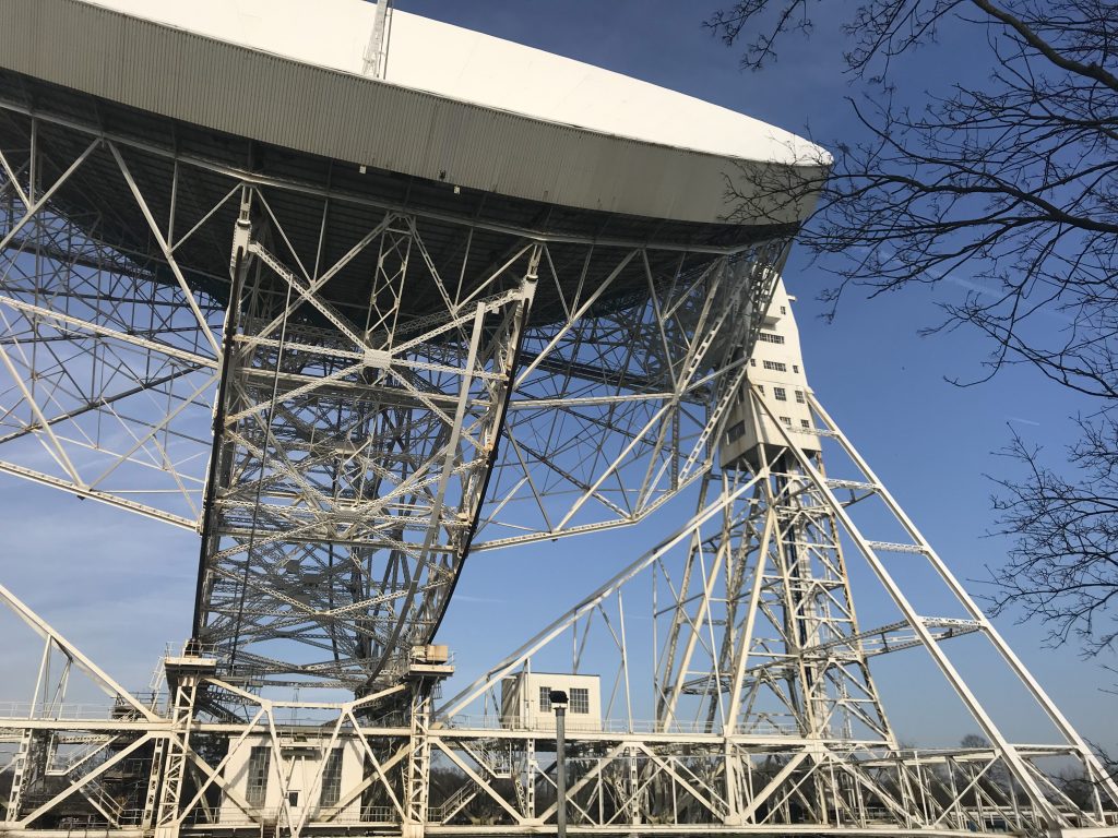 Looking up at a very large satellite dish on a complicated structure of steel bars and struts.