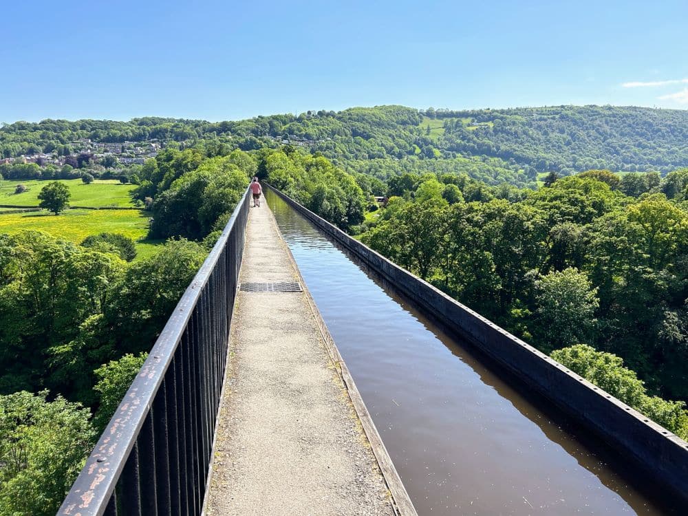 A view along the footpath next to the canal: straight ahead, a narrow path with a railing on the left. Next to it, a narrow canal.