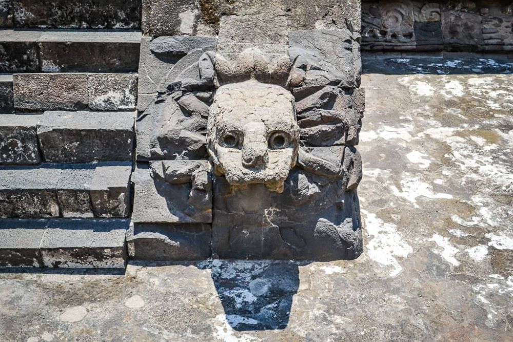 A serpent's face carved from stone, looking very human.