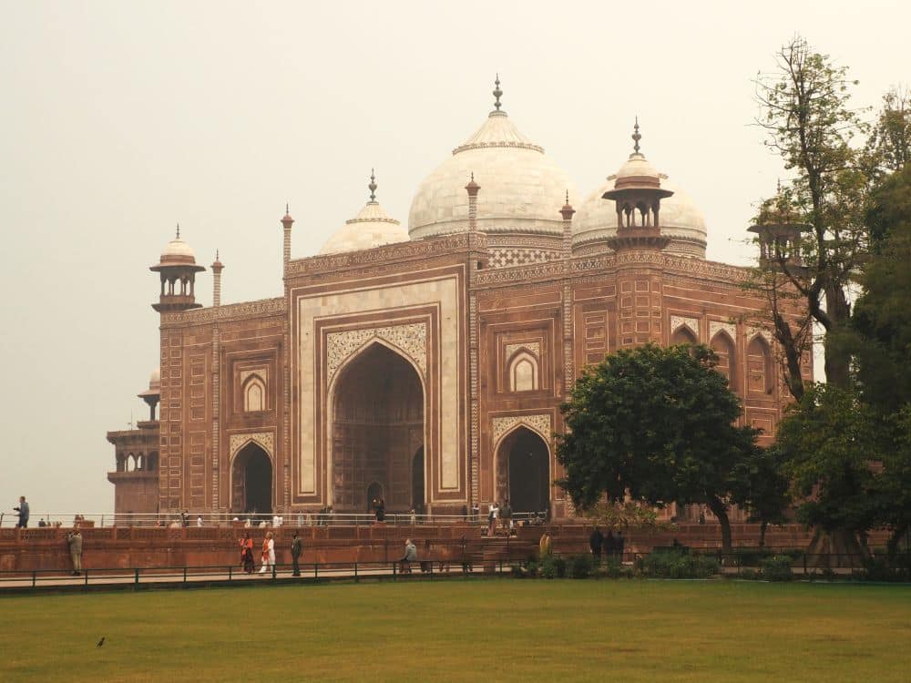 A large building of red sandstone with white accents and a white central dome.