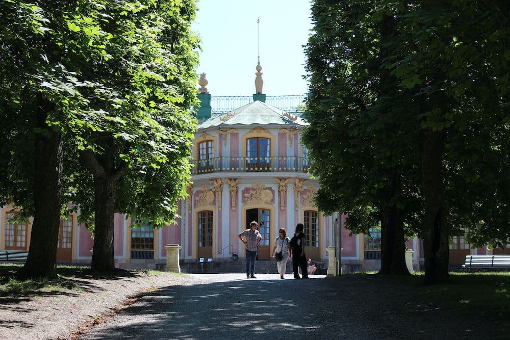 A small but elegant building visible between a line of trees.