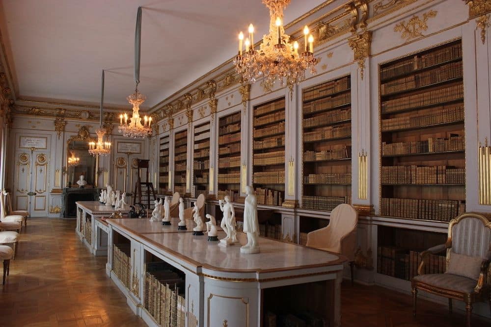 An elegant library with built-in shelves and chandeliers.