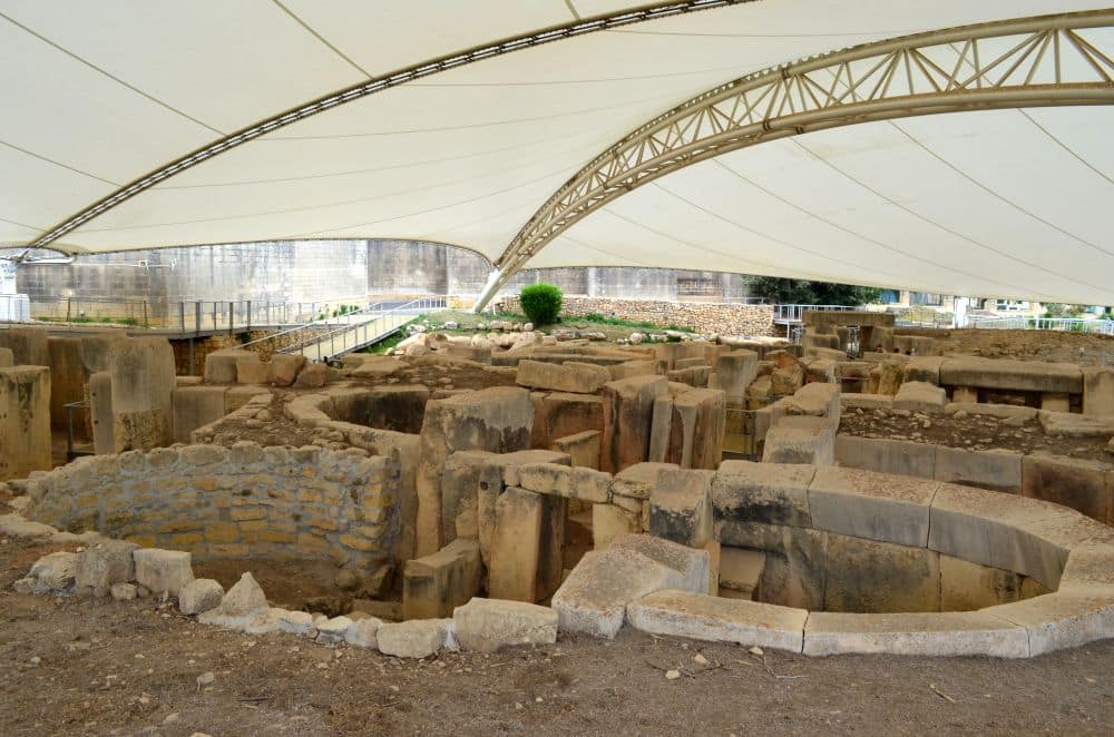 Remains of rounded walls underneath a large permanent tent roof.
